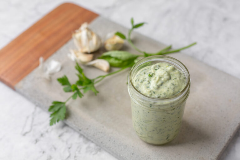 Green Goddess dressing in a mason jar on a grey and wood cutting board