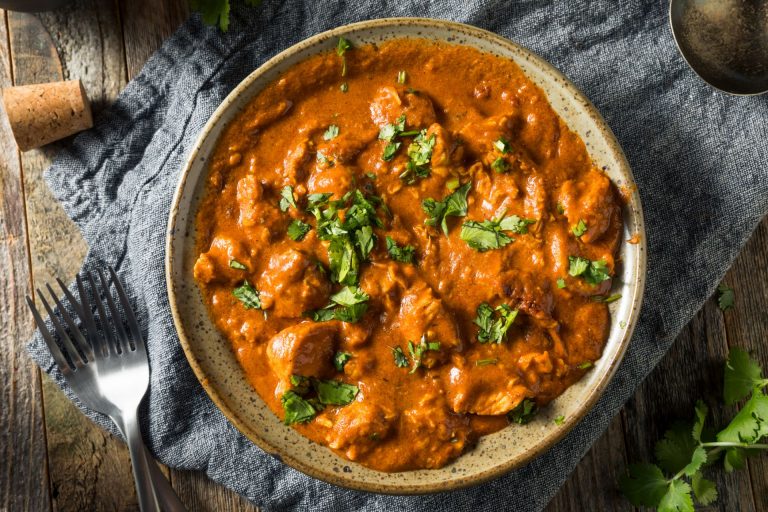 Quick butter chicken in a beige bowl topped with chopped cilantro