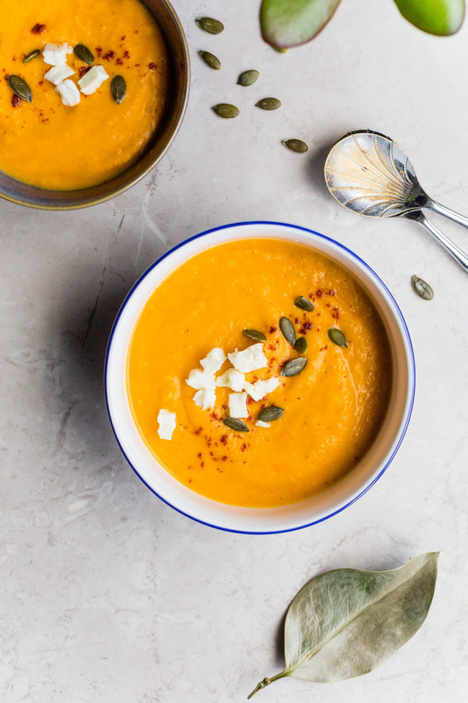 bowl of soup with cheese and pumpkin seeds on top
