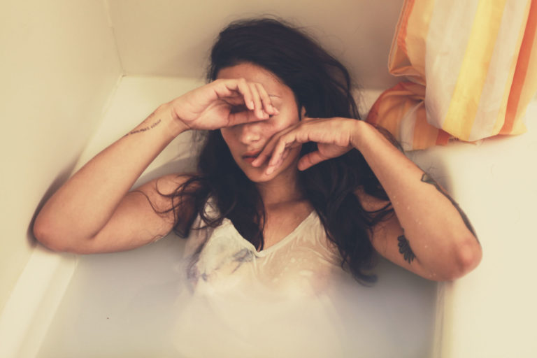 woman sitting in bathtub looking sad