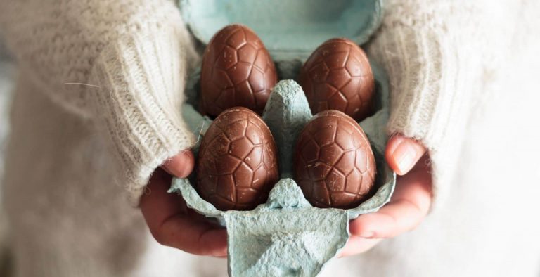 Person in a white sweater holding a turquoise cardboard container of chocolate eggs, before making deep-fried Easter creme eggs