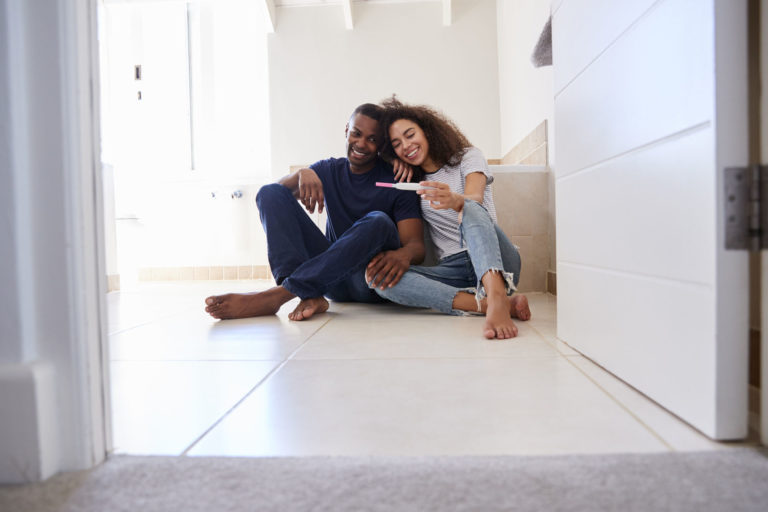 a couple sits with positive pregnancy test