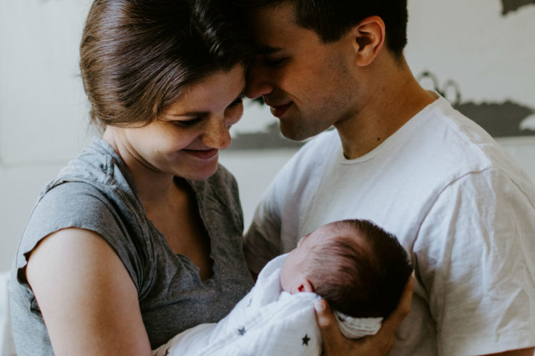 mom and dad holding their swaddled baby