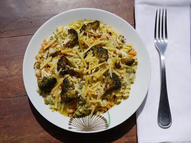 Creamy zucchini pasta with crispy broccoli on a white plate