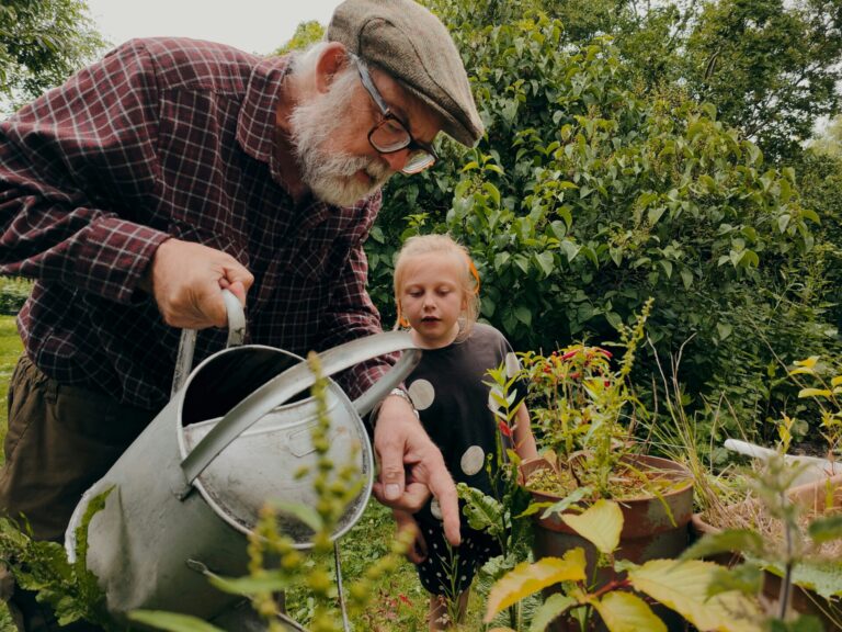 Grandfather explanining something in the garden to grandchild, to illustrate making contributions to grandchildren from birth