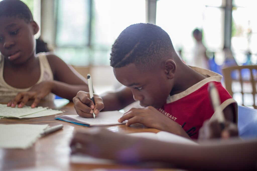 Child concentrating on a writing assignment, to illustrate setting high expectations for all kids