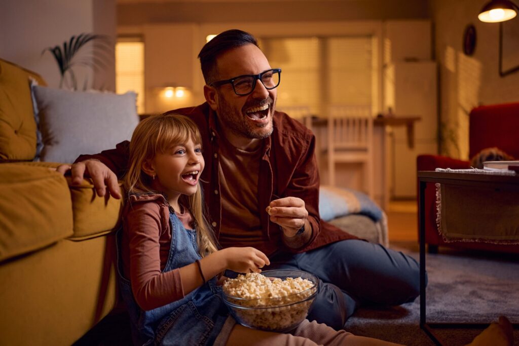 parent and child are watching TV excitedly. Maybe they're tuned into 90s tv shows