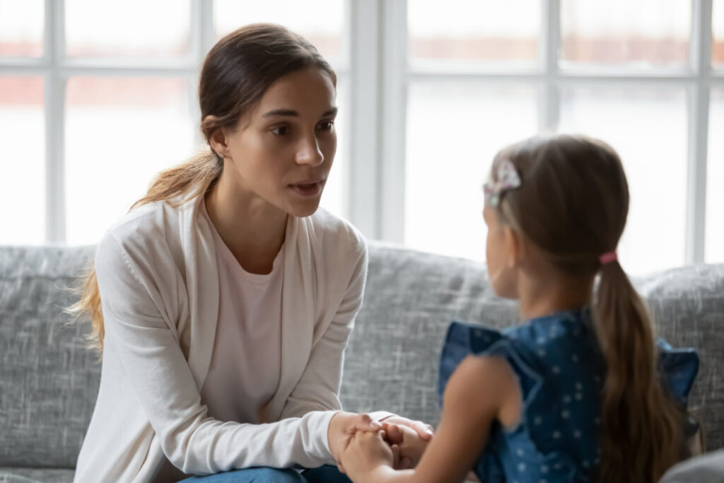 Woman holding her child's hands and apologizing, to illustrate how to repair after yelling at kids