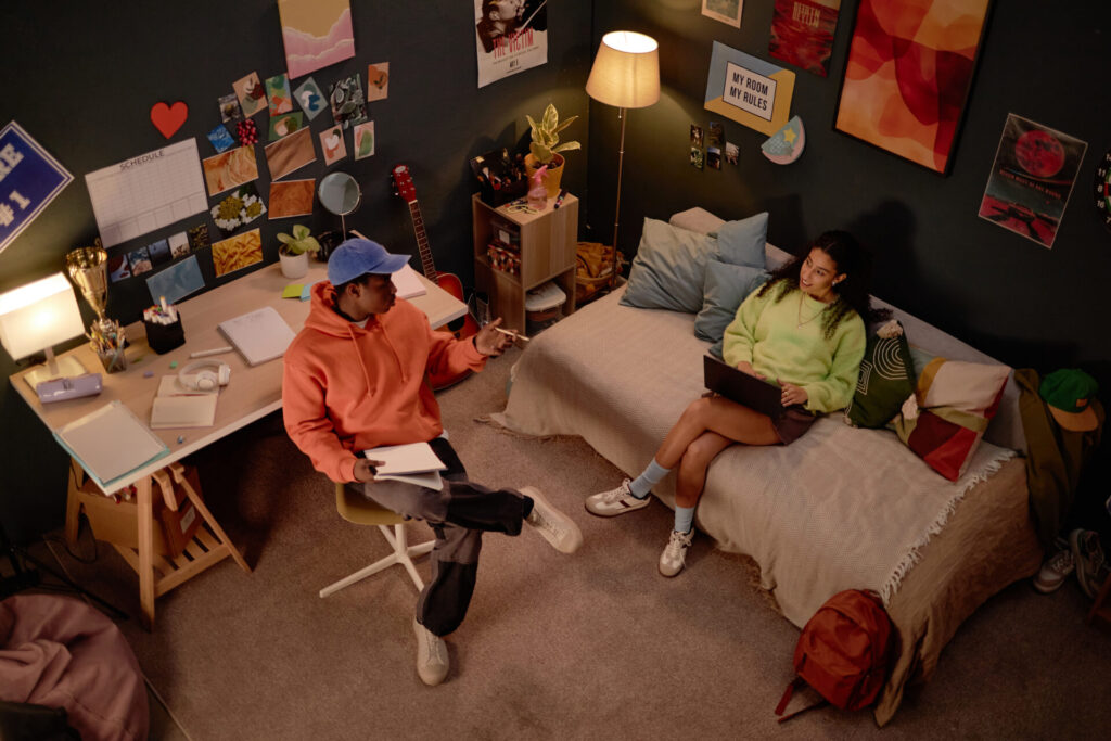 Teenagers sitting in a personalized dorm room, not the work of a dorm room designer