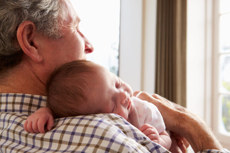 Grandfather in a plaid short holding newborn, to illustrate grandparent names worth considering